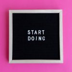 Black letter board with 'Start Doing' motivational text on bright pink background.